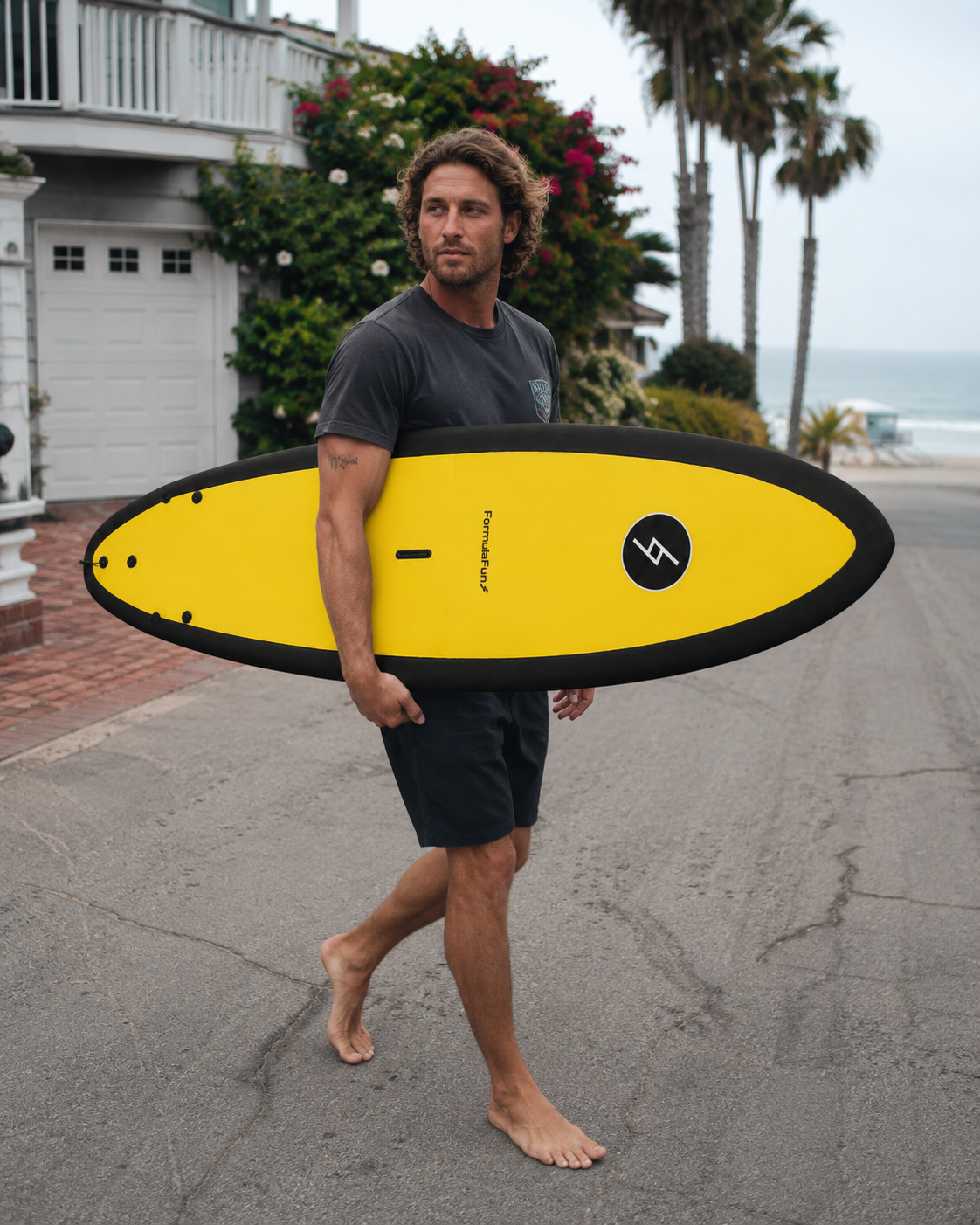 Surfer carrying a yellow Formula Fun 6'0" Jam board near the beach