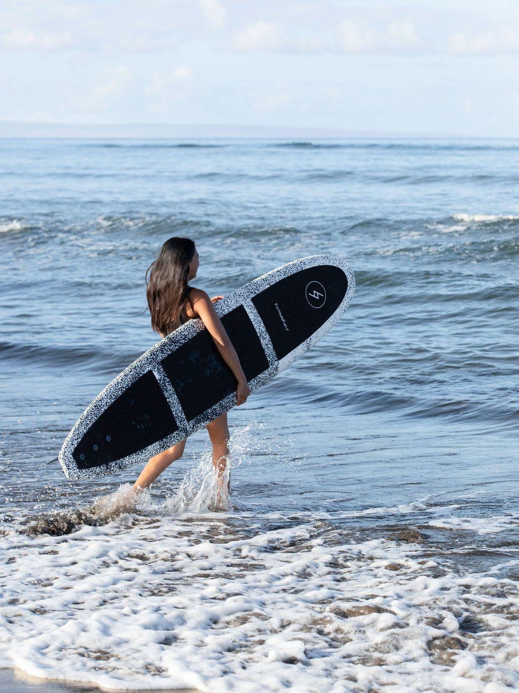 Woman walking into the ocean with a speckled 8 foot Formula Fun Foamies Rincon