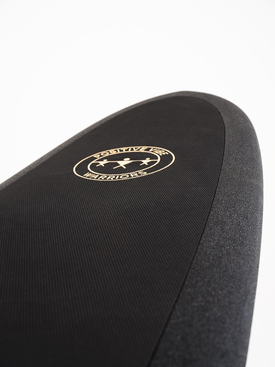 The front wax free deck pad of a black 8 foot Positive Vibe Warriors Scout surfboard with a logo on a white background