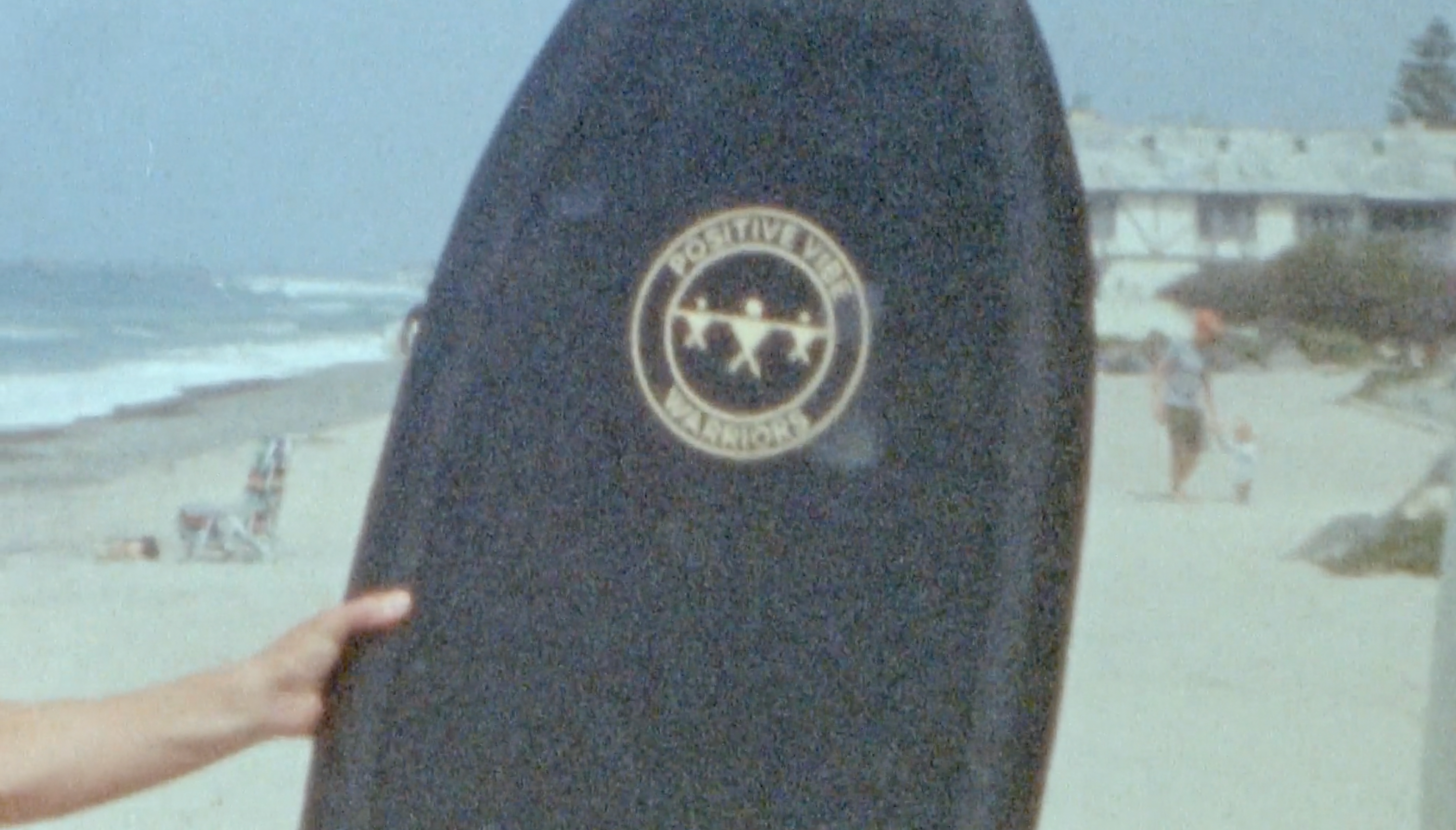 A vintage photography of a black Positive Vibe Warriors Slide Boogie Board on a beach