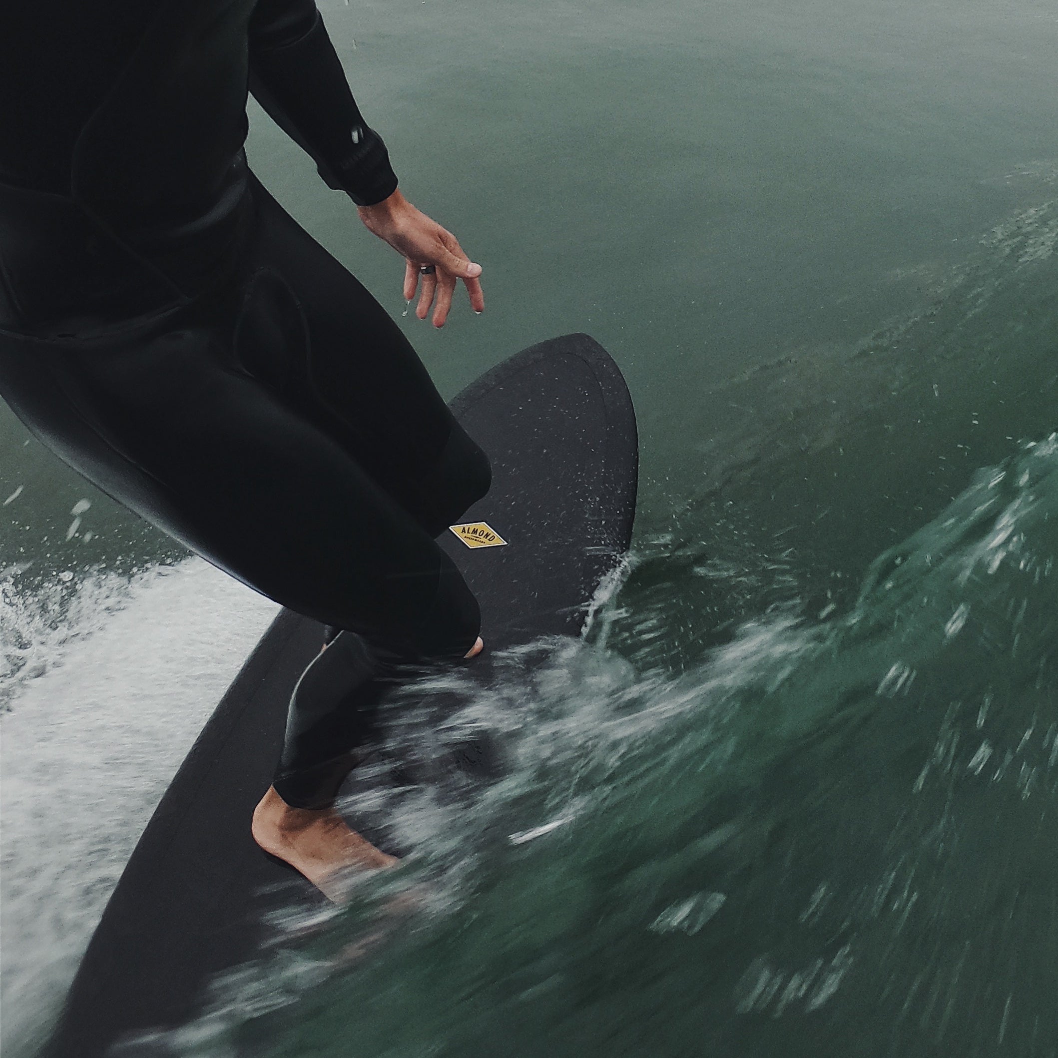 Man surfing a wave on a black 6 foot 4 inch Almond Plez Phez surfboard