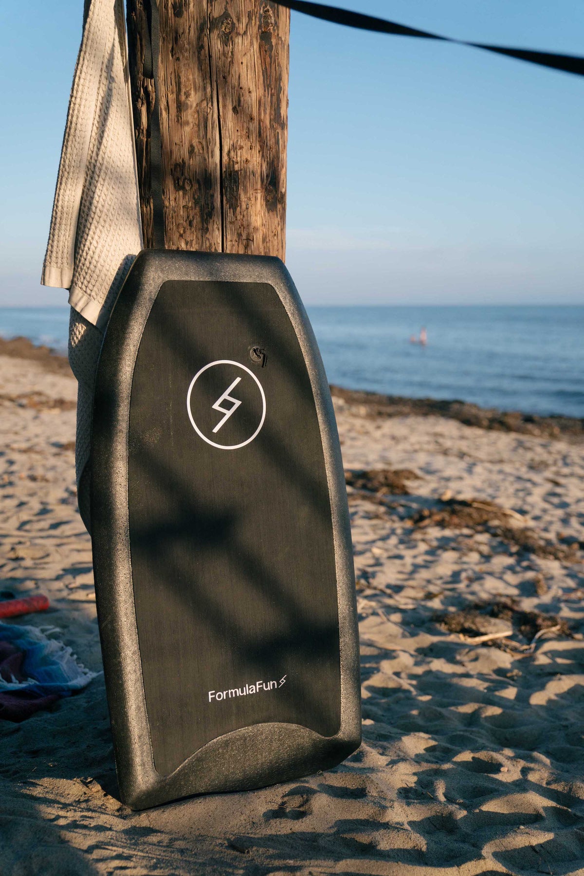Black Formula Fun 42.5-inch Body Board standing upright on a beach