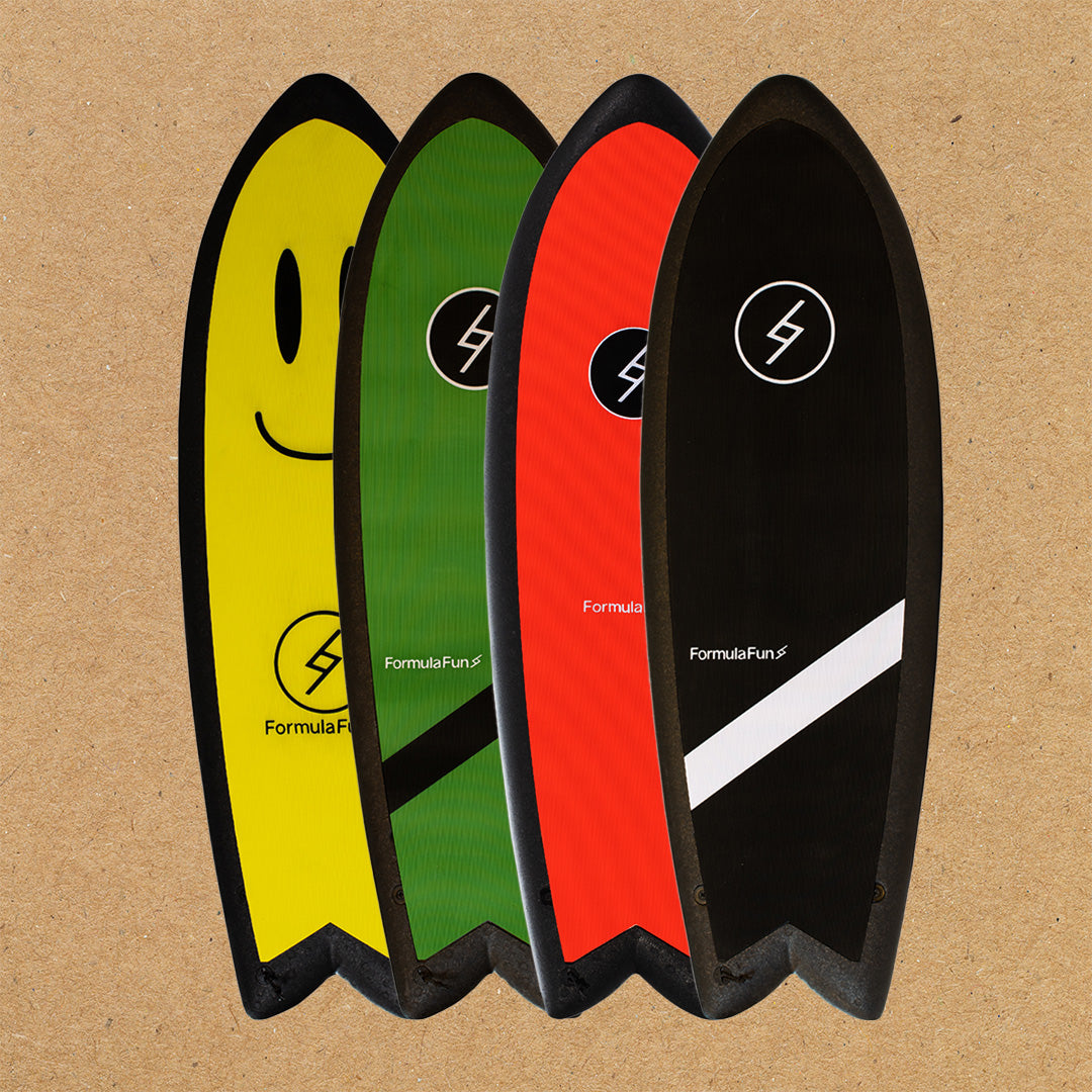 A yellow, a green, a red and a black 5 foot 3 inch Formula Fun Foamies Twinnie surfboard on a light brown background