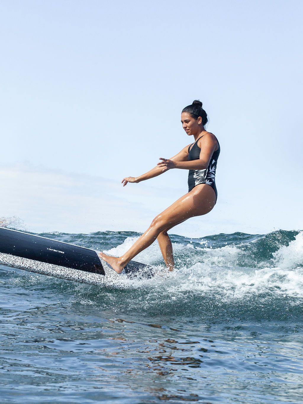 A woman surfing a wave on a speckled 9 foot 6 inch Formula Fun Foamies SanO