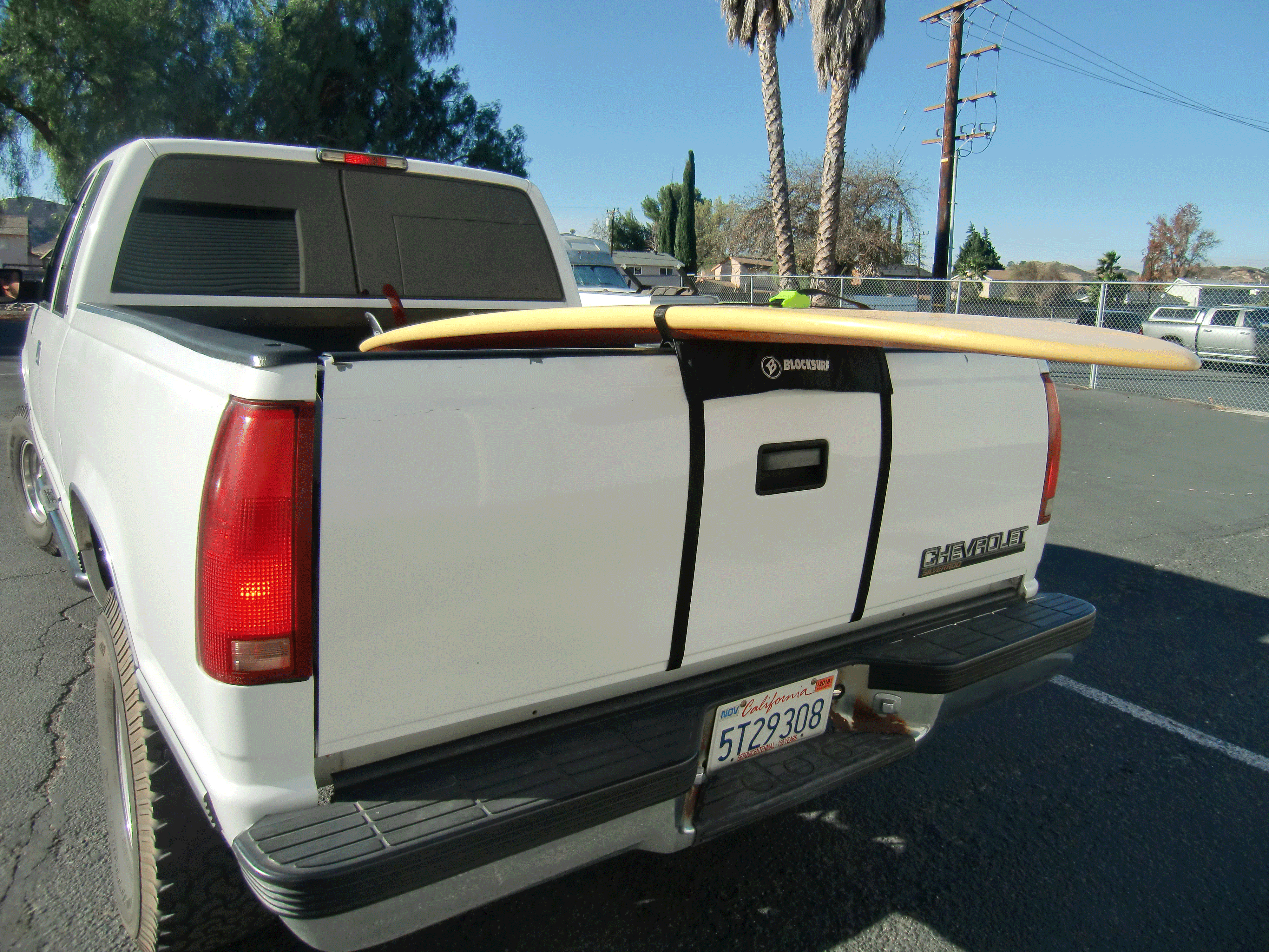 White truck with a Tailgate Rack Pad keeping a yellow surfboard off the tailgate