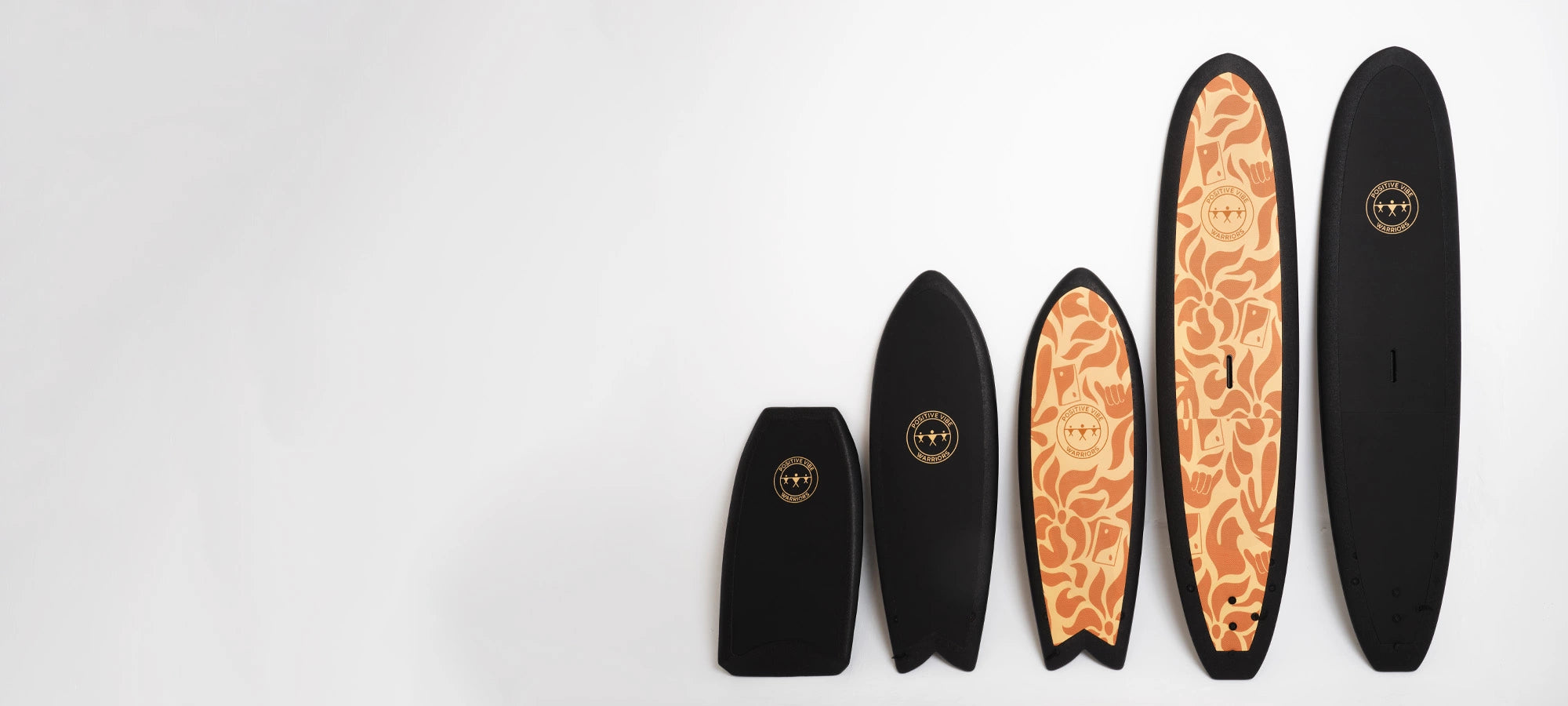 Positive Vibe Warriors surfboards of all shapes and sizes standing next to each other in a studio setting