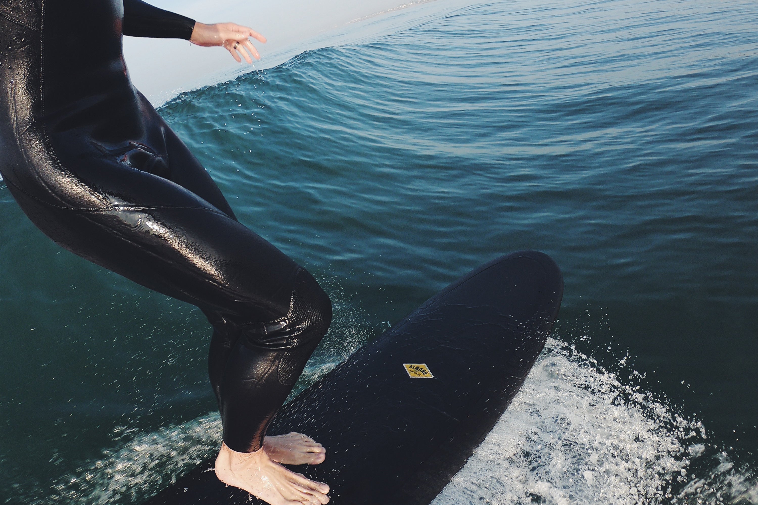 Man surfing a wave on a black 9 foot 2 inch Almond Surf Thump surfboard