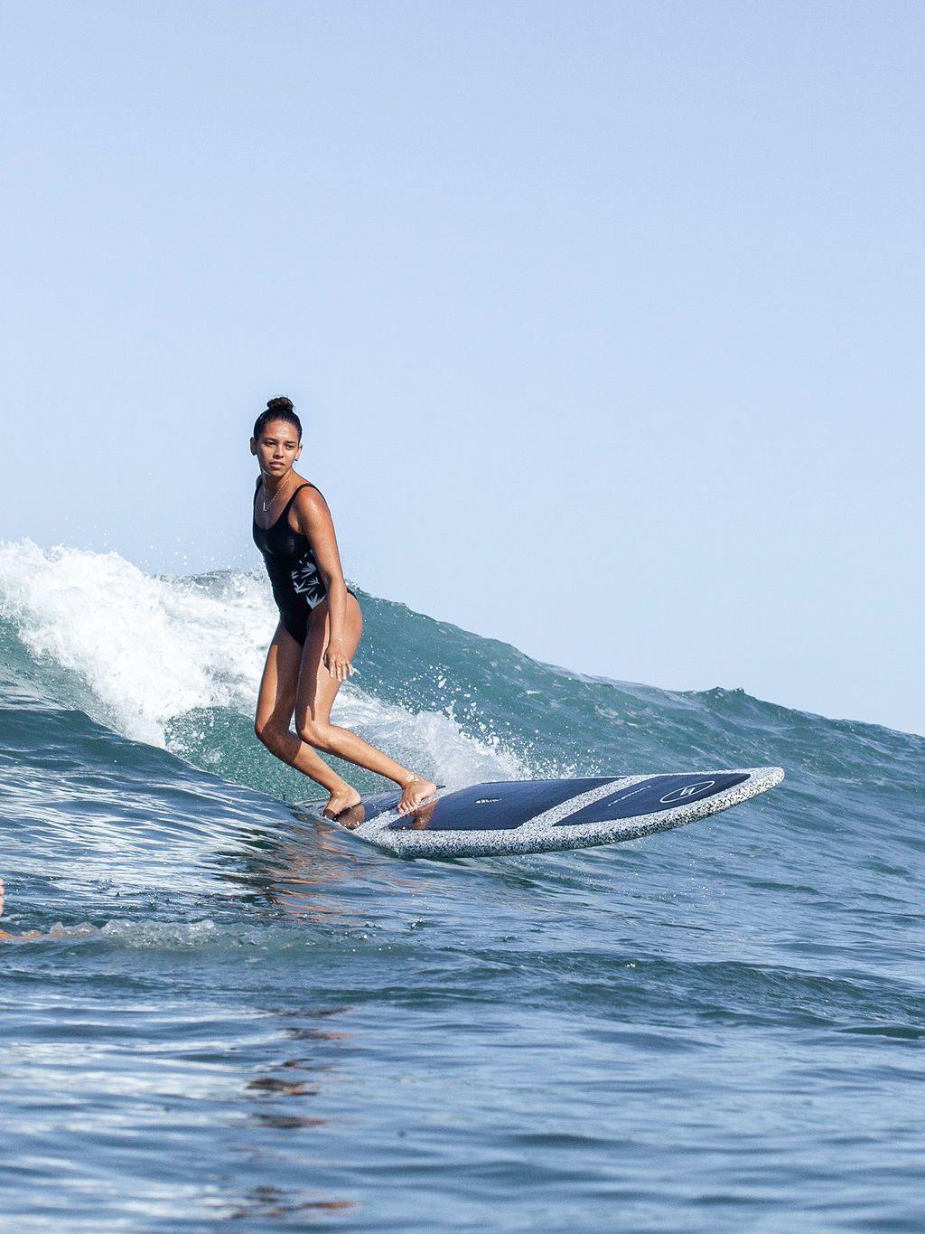A woman surfing a wave on a speckled 9 foot 6 inch Formula Fun Foamies SanO